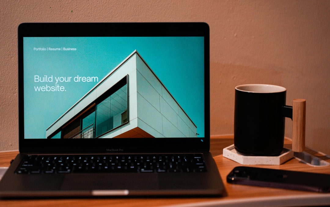 hero-img Build your dream website for your future. A laptop, MacBook, on top of a portable table with coffee tea mug on the side.